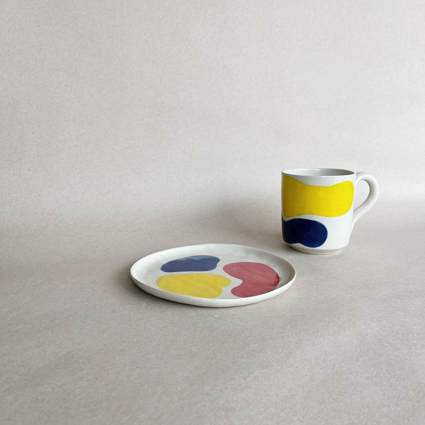 handmade ceramic tricolor mug on the side of tricolor dessert plate