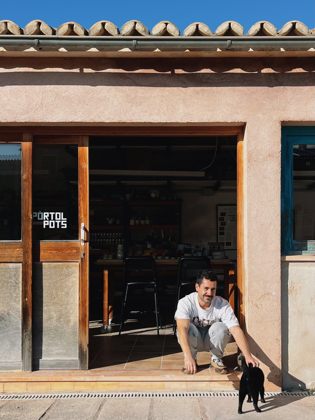 Joan and Pepa the studio cat standing at the entrance of the pottery workshop in Pòrtol, Mallorca.